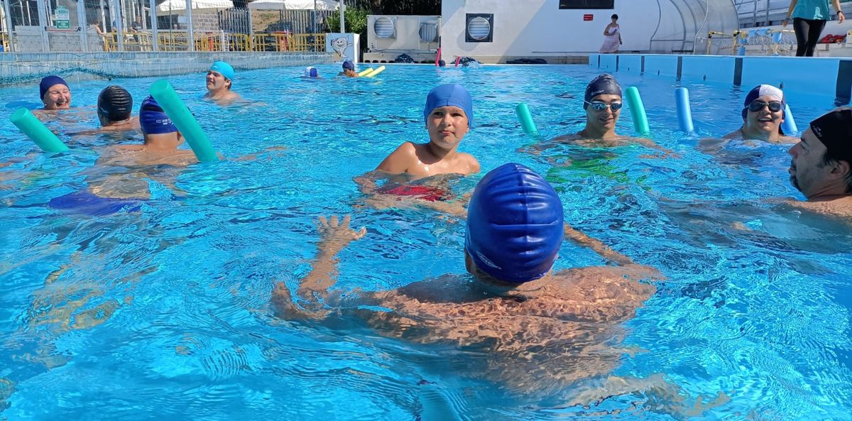 sessione in piscina del corso ripresa all'altezza dell'acqua con vari ragazze e ragazzi e istruttori e istruttrici in acqua